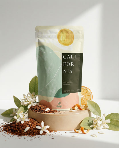 CALIFORNIA Rooibos & Orange Tee von Alandas – elegante Verpackung mit frischen Orangen und Blüten auf Podest
