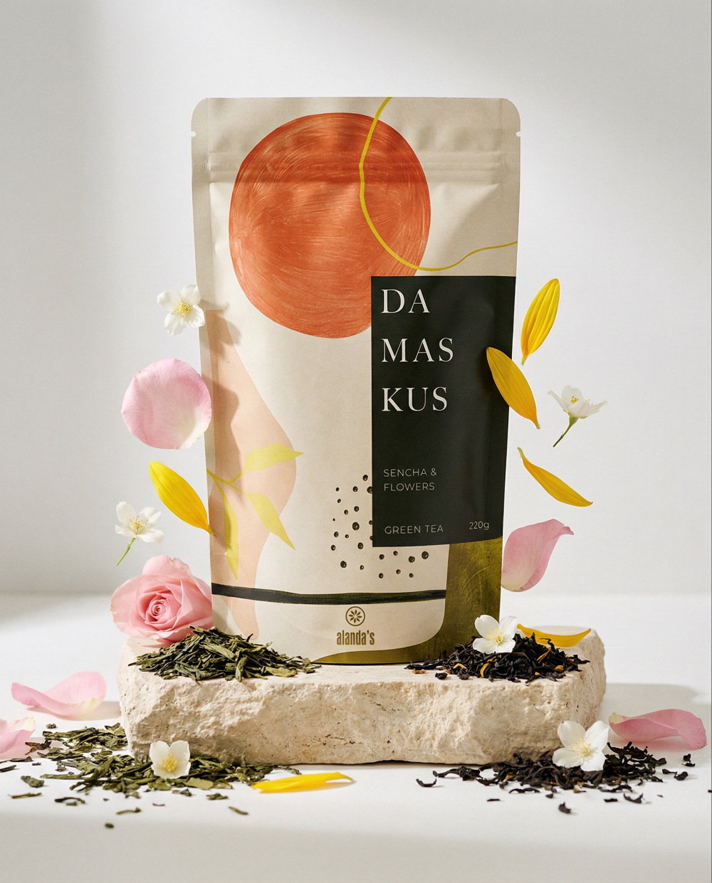 DAMASKUS Sencha & Blüten Tee von Alanda's – Produktfoto mit Teebeutel, Rosen, Jasminblüten und losem Grüntee auf Naturstein