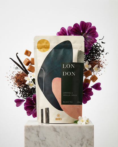 LONDON Schwarztee Karamell Vanille Jasmin von Alandas in eleganter Verpackung mit Blumen und Gewürzen auf Marmorsockel