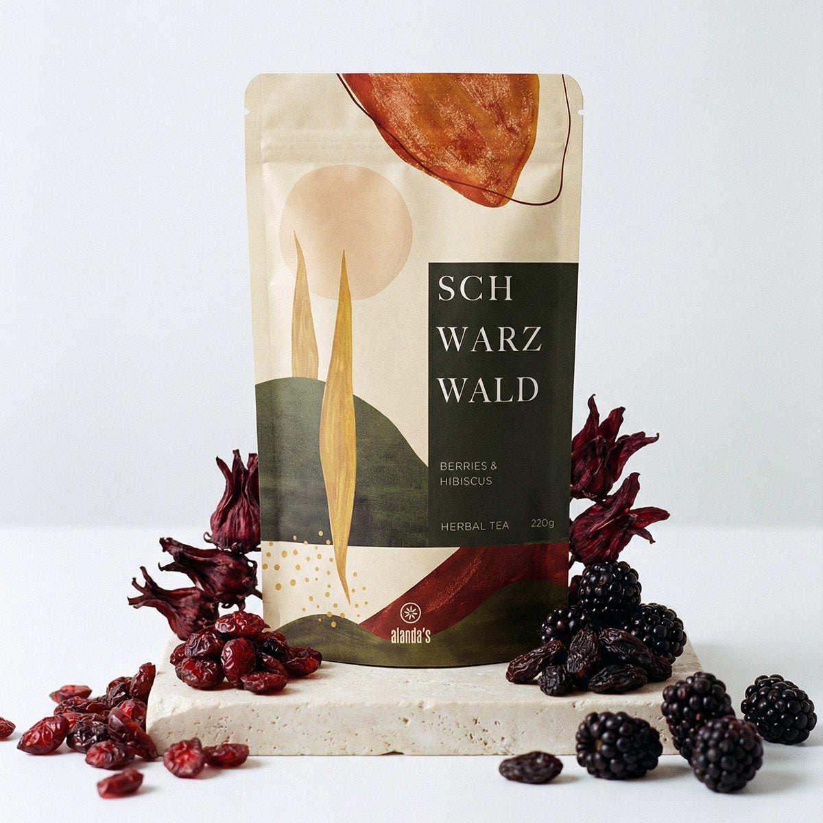 Alanda's Tea SCHWARZWALD Doypack mit Brombeeren, Preiselbeeren und Hibiskusblüten auf Steinpodest